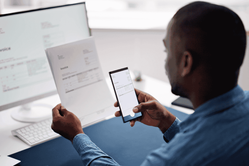 Entrepreneur numérisant une facture sur smartphone pour obtenir un financement rapide via l’affacturage ou la cession Dailly.