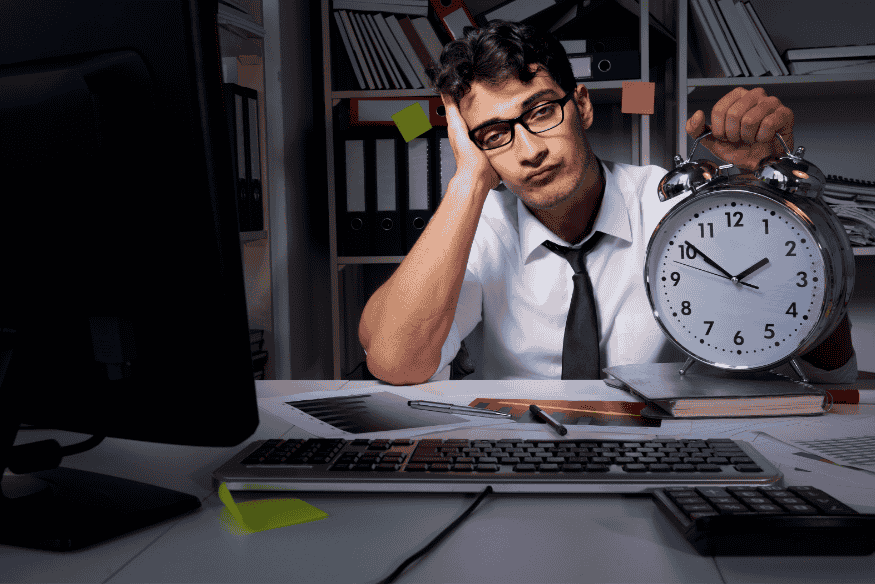 Entrepreneur fatigué face à une horloge symbolisant les retards de paiement et la pression sur la trésorerie d’entreprise.