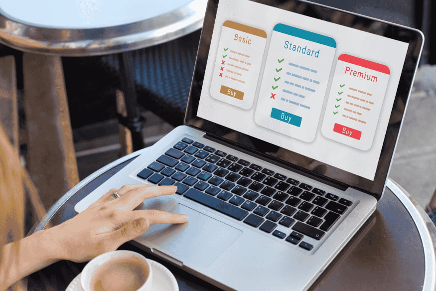 Personne utilisant un ordinateur portable affichant trois formules d’abonnement : basic, standard et premium avec leurs caractéristiques