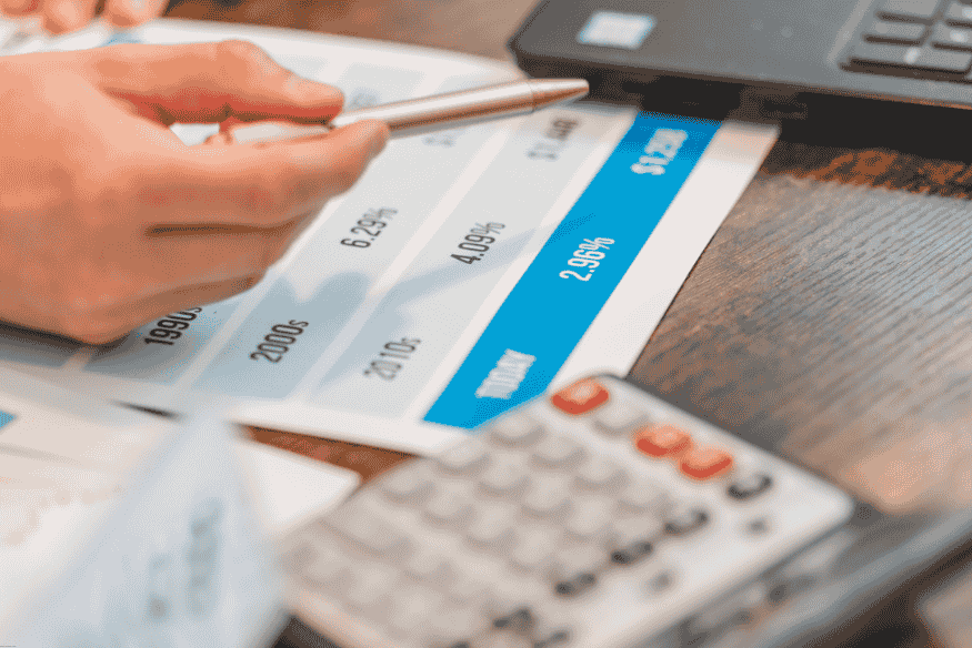 Main tenant un stylo au-dessus d’un tableau de taux d’intérêt.