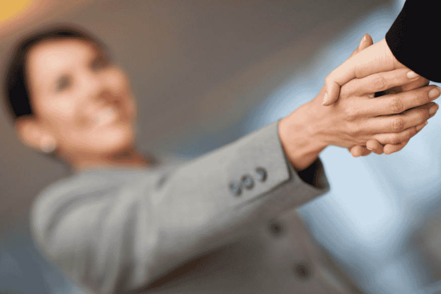 Poignée de main entre deux personnes floues, symbolisant un accord financier.