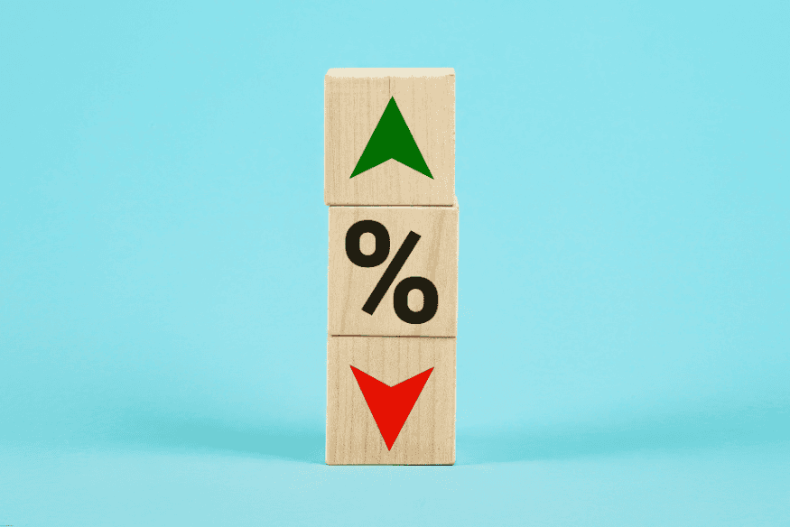 Trois blocs en bois empilés avec un symbole de pourcentage, une flèche verte vers le haut et une rouge vers le bas.